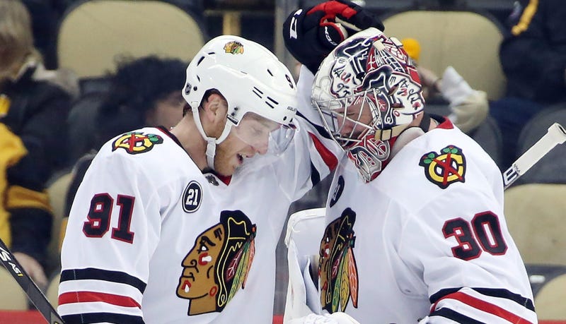 Blackhawks center Drake Caggiula (91) and goalie Cam Ward (30) celebrate after beating the Penguins.