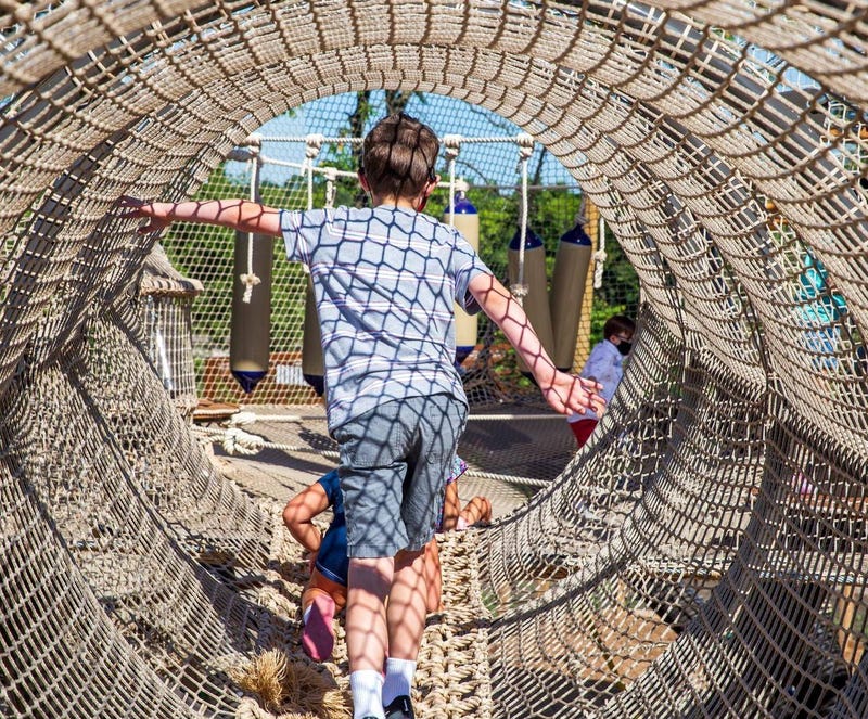 child walking through rope tunnel outside