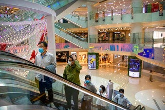 In this April 15, 2020 photo, people wear facemasks to protect against the spread of the new coronavirus as they ride an escalator at a shopping mall in Beijing. China. (AP Photo/Mark Schiefelbein)