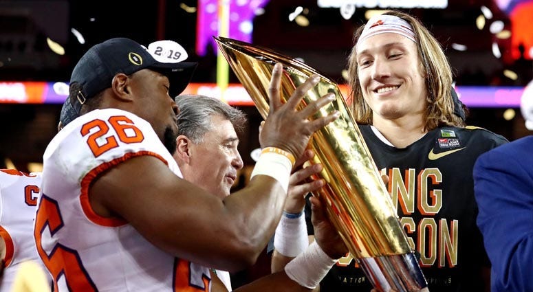 Clemson quarterback Trevor Lawrence, right, celebrates with the national championship trophy after beating Alabama during the College Football Playoff championship game on Jan. 7, 2019, at Levi's Stadium in Santa Clara, California. 