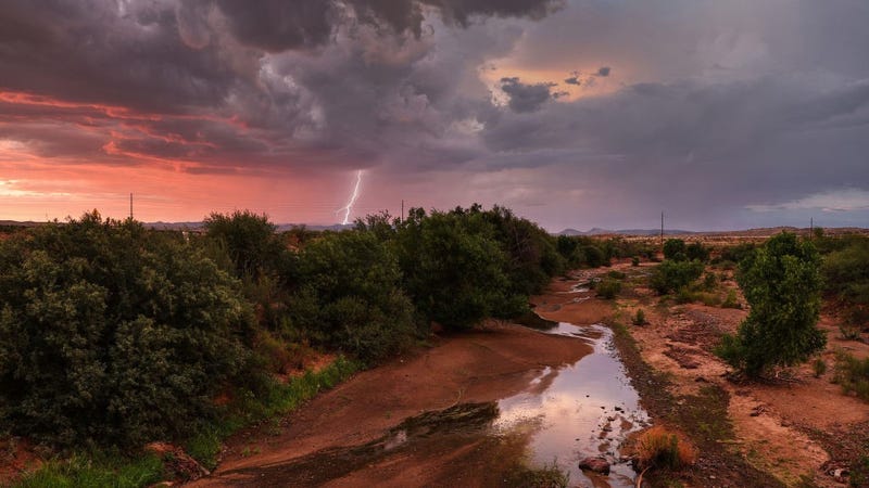  Lightning strikes during a monsoon storm with a nearly dry creek bed in the foreground on July 21, 2022 near Mayer, Arizona.