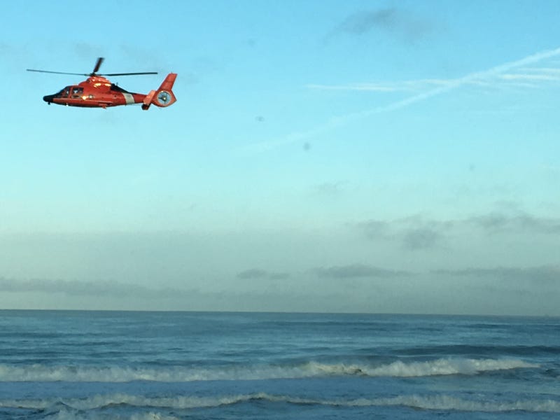 A helicopter flies above the Pacifica coastline, searching for a missing swimmer on March 26, 2019.