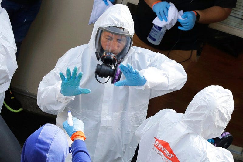 Servpro cleaning workers are sprayed as they exit the Life Care Center in Kirkland, Wash., Thursday, March 12, 2020, at the end of a day spent cleaning inside the facility near Seattle. (AP Photo/Ted S. Warren)
