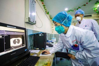 Doctors look at a CT scan of a patient at a hospital in Wuhan in central China's Hubei Province, Thursday, Jan. 30, 2020. China counted 170 deaths from a new virus Thursday and more countries reported infections. (Chinatopix via AP)