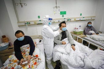 A doctor checks the conditions of a patient in Jinyintan Hospital, designated for critical COVID-19 patients, in Wuhan in central China's Hubei province Thursday, Feb. 13, 2020. (Chinatopix Via AP)