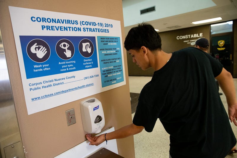 A man uses hand sanitizer underneath a coronavirus prevention sign at the entrance of the Nueces County Courthouse on Friday, March 13, 2020. Covid 19 Corpus 6