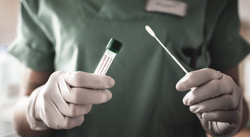 A nurse holds a swab and test tube ready to administer a covid-19 test