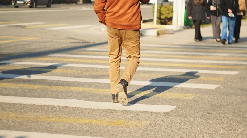 Man crossing street at pedestrian crosswalk - stock photo