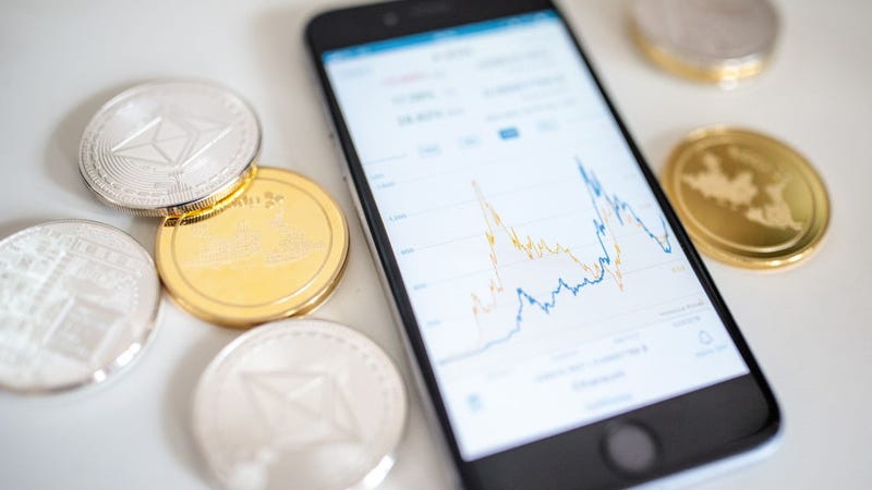 In this photo illustration of the litecoin, ripple and ethereum cryptocurrency 'altcoins' sit arranged for a photograph beside a smartphone displaying the current price chart for ethereum on April 25, 2018 in London, England. 