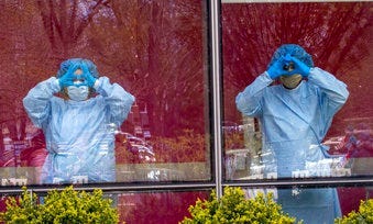Nurses gesture from inside the hospital as others hold a demonstration outside Jacobi Medical Center to protest a new policy by the hospital requiring a doctor's note for paid sick leave. (AP Photo/Mary Altaffer)