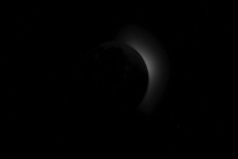 Solar corona appearing from behind the Moon. Lunar features appear to be visible illuminated by Earth's light, particularly Mare Imbrium and the ray systems of Copernicus and Kepler.