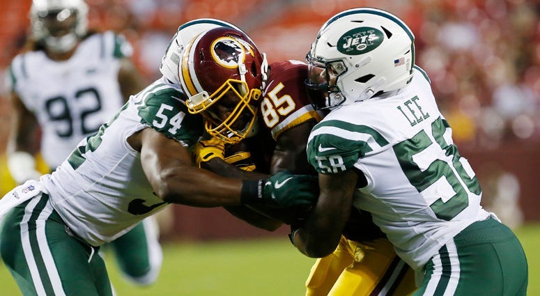 Jets linebacker Darron Lee (58) attempts to stop Redskins tight end Vernon Davis on Aug. 16, 2018, at FedEx Stadium in Landover, Maryland.