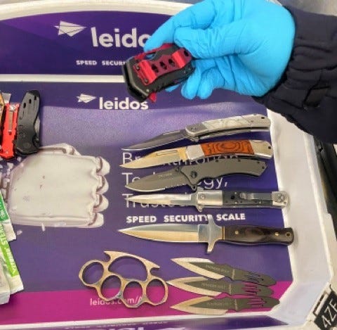A TSA officer picks up a knife, one of many weapons that were detected in a traveler’s carry-on bag at DCA on May 4. 
