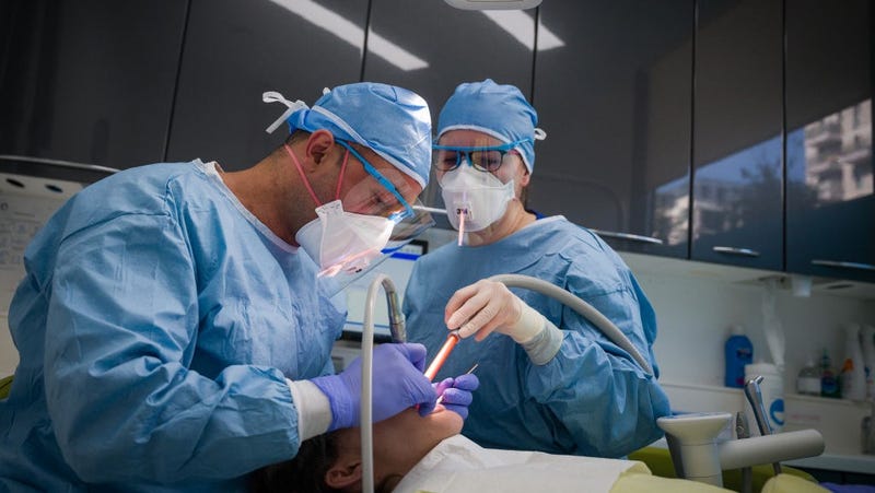  Dentist Fiez Mughal (L) and Dental Nurse Johanna Bartha (R) carry out a procedure on a patient in one of the six surgery rooms at East Village dental practice on May 28, 2020 in London, England.