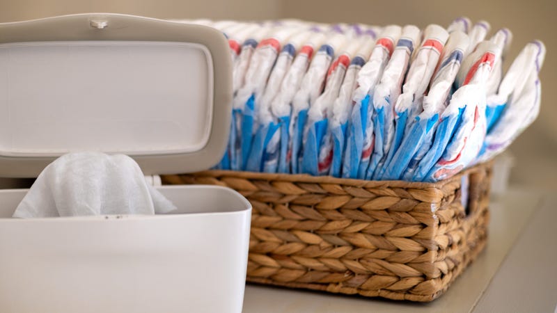 a diaper wipe bin open with a basket of diapers in the background