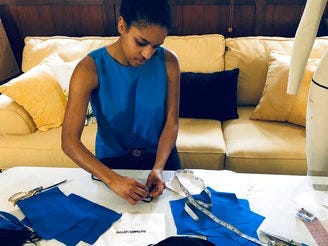 In this Sunday, March 22, 2020, photo, provided by Christina Hunter, Briana Danyele sews cloth face masks that say "We Got This!" in her mother's living room in Greer, S.C., which will be sent to health care workers. (Christina Hunter via AP)