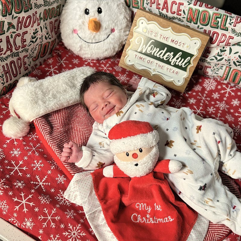 Baby in winter onesie with My 1st Christmas Santa doll