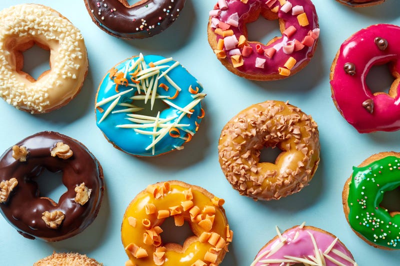 A plate with donuts in a variety of colors and flavors