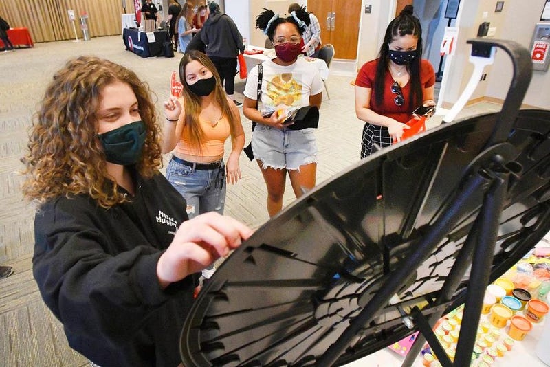 Illinois State University students Rhiannon Pschirrer, left, Jasminh Randall, Alexis Robles and Michaela Dennis try out there hand on a wheel of fortune as they participate in the school's alternative spring break giveaways at Bone Student Center in Normal, Ill., Tuesday, March 9, 2021.