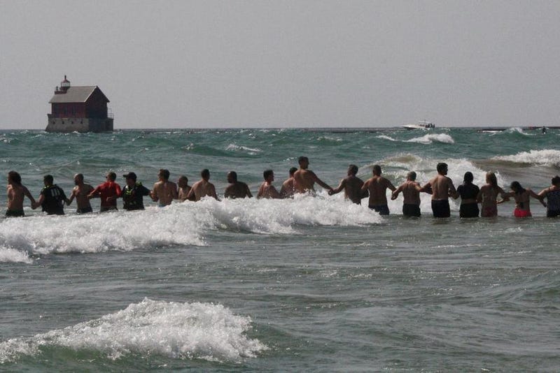 FILE - In this Aug. 5, 2018 file photo, beachgoers help Grand Haven Department of Public Safety officers form human chains to search for missing people in Lake Michigan at Grand Haven State Park in Grand Haven, Mich. More drownings have been reported in the Great Lakes so far in 2021 than by this time last year, prompting officials to urge swimmers to practice water safety measures. As of July 2, there were 32 drownings in the Great Lakes, compared to 25 as of July 4, 2020, according to data collected by the Great Lakes Surf Rescue Project.