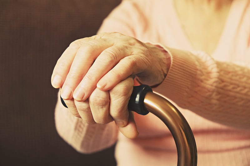 Elderly woman in nursing home, wrinkled hand with clearly visible veins holding walking quad cane