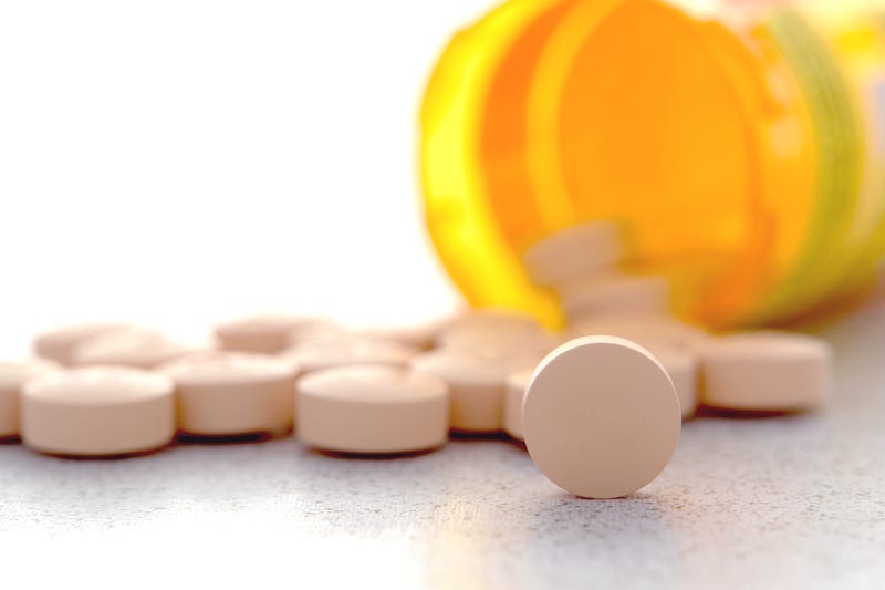 Prescription pain RX medication pills spilled out of an amber pharmacy medicine bottle on a pharmacy counter