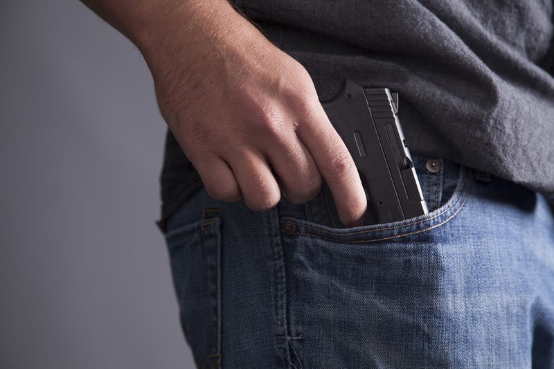 A man legally carries a firearm in his pocket for protection.