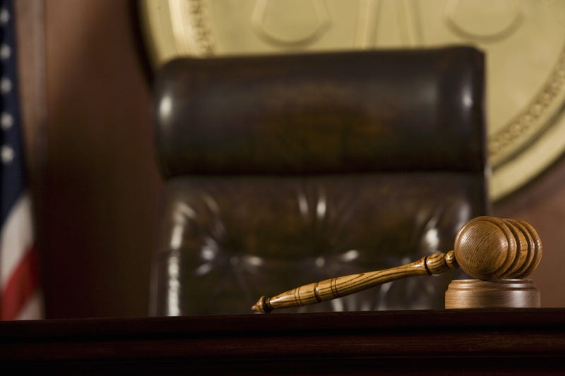 Wooden gavel lying on table by judge's chair in courtroom