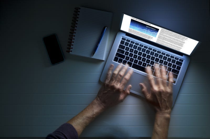 Hands using a laptop computer at night or in the dark, with a business article on the screen