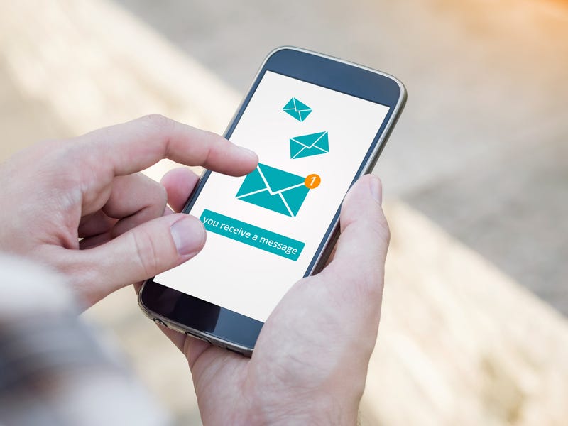 Email app on smartphone screen. You receive a message, New message is received. Man's Hand holding a smartphone