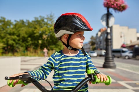 Kid with bike and helmet smiles while having fun