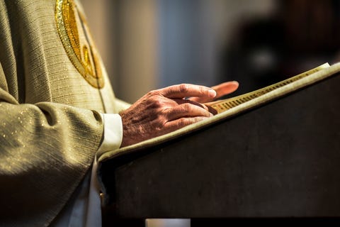 Hands of catholic priest reading a bible