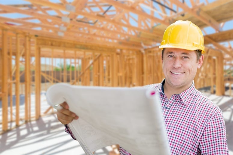 Contractor With Plans On Site Inside New Home Construction Framing