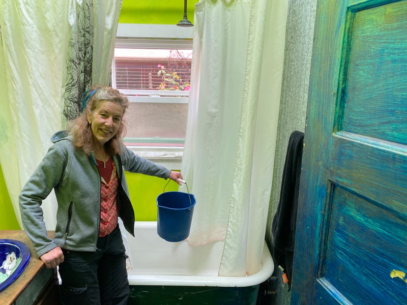 Elizabeth Dougherty, director of Whole H2O, demonstrates some of her water conserving strategies including a bucket in the shower.