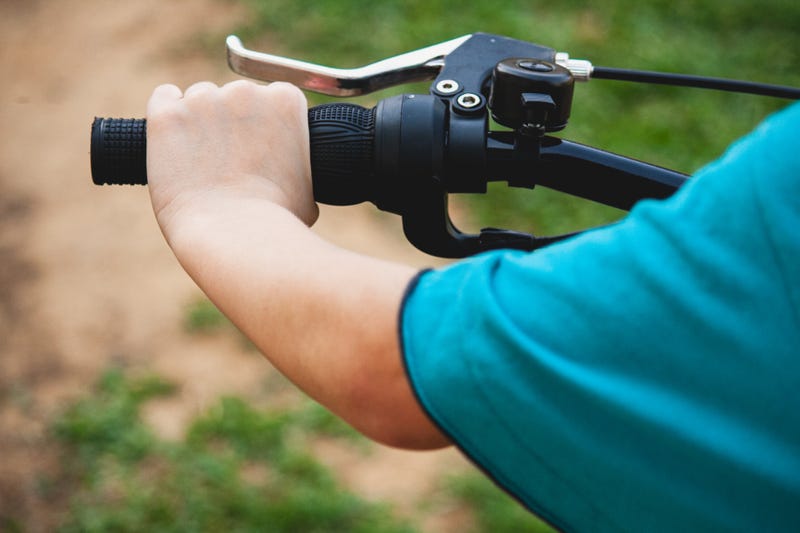 A small child grabbing onto a bike handle
