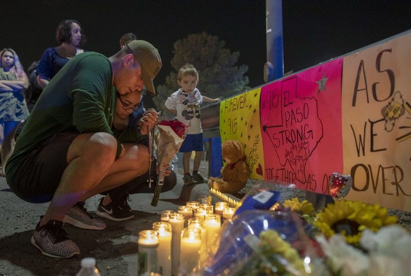 people mourn at a vigil after a shooting in an El Paso Walmart