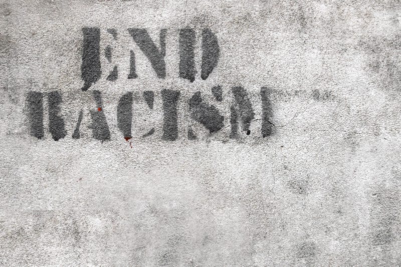 Graffiti on brick wall reads END RACISM
