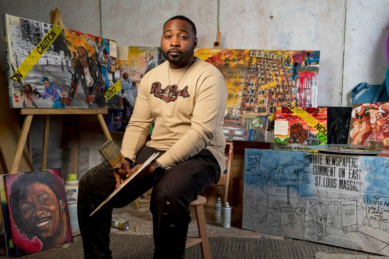 Mykael Ash sits among his art pieces