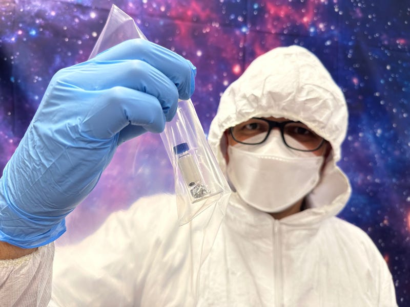 Field Museum Curator for Meteoritics and Polar Studies holds up a sample of asteroid Bennu. 
