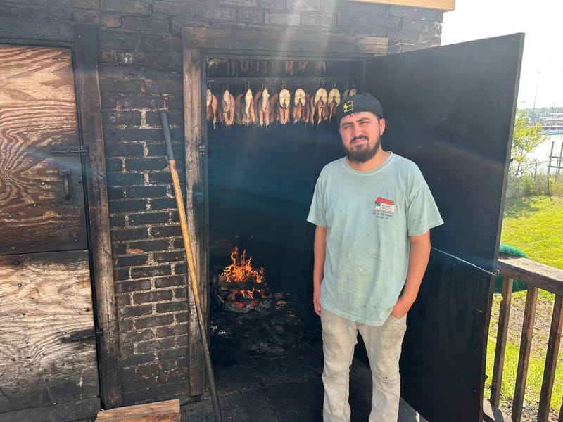 man standing outside fish smoker on a hot day