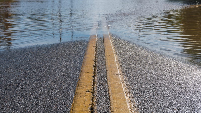 Road with yellow center stripe leading into flooded area on the horizon