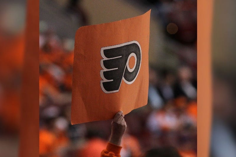 A hockey fan holds up a Flyers logo