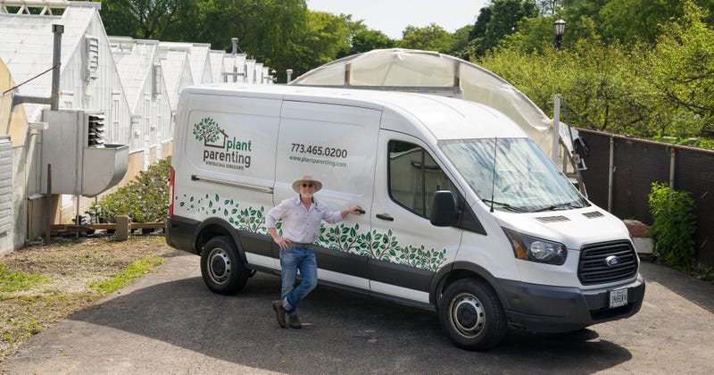 Nursery owner stands next to his Ford Transit van at greenhouse complex
