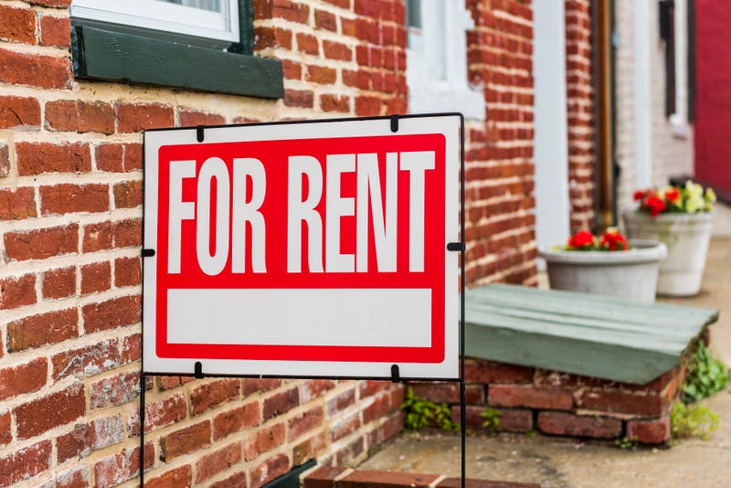 Red for rent sign closeup against brick building