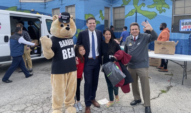 State Rep. Jared Solomon (center) and businessman Gary Barbera (right) pose with a woman and child, and the Barbera Bear.