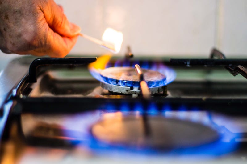 hand lighting gas jets on stove