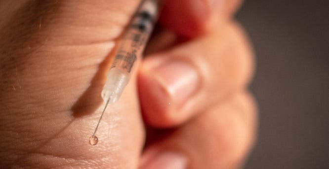 Close-up image of hypodermic needle in person's hand