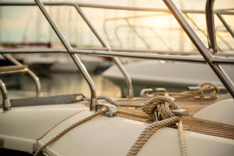 White mooring rope tied around steel anchor on boat