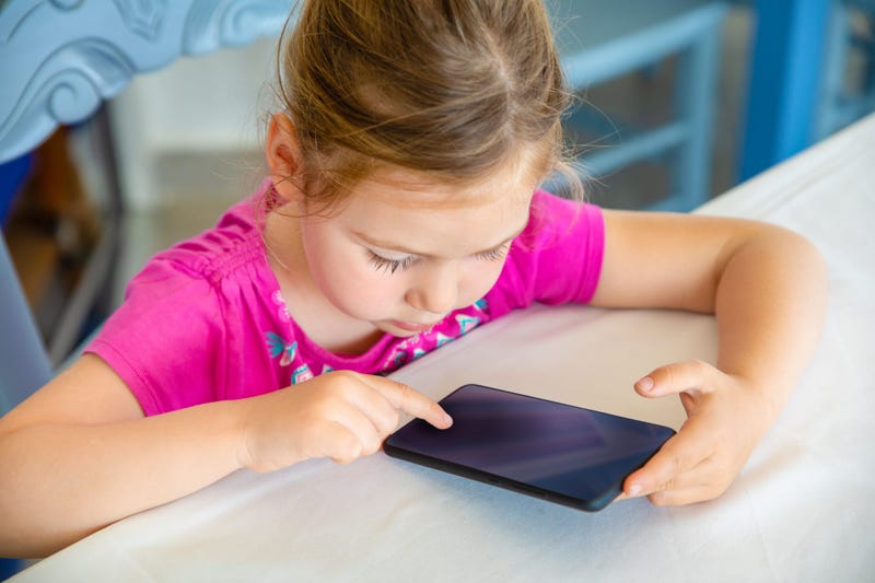 Little girl uses a small touch-screen device.