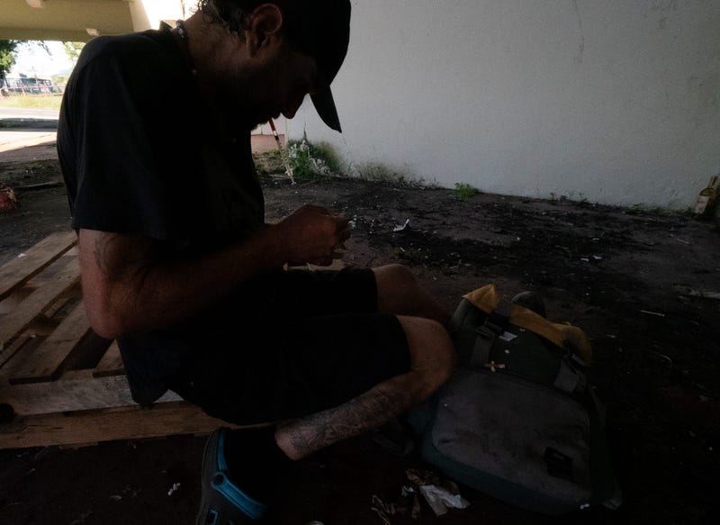 A heroin addict prepares to shoot up outside